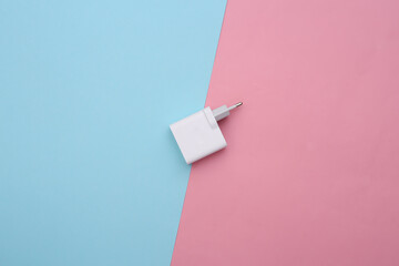 Charger adapter on a blue-pink pastel background. Top view. Minimalism flat lay