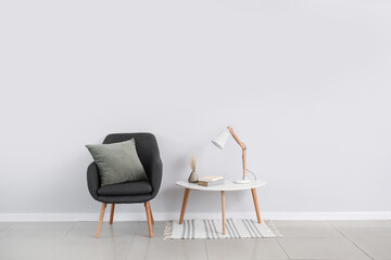 Stylish armchair and table near light wall