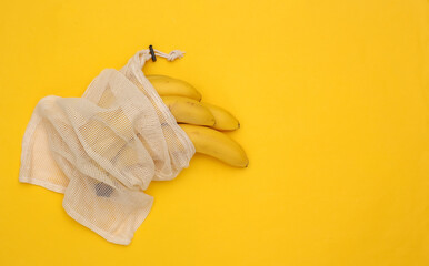 Eco cotton bag with ripe bananas on yellow background with copy space. Top view. Flat lay