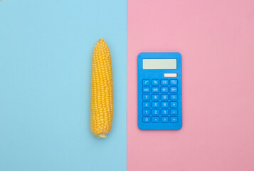 Swing of corn and calculator on pink blue background. Flat lay composition. Top view