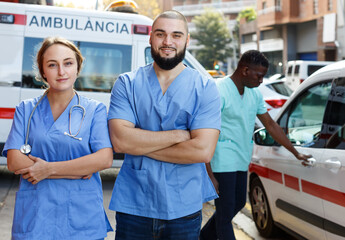 Portrait of smiling male and female paramedicals near ambulance car outdoor