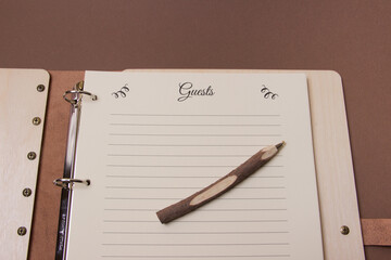 close up of opened wooden guests book with pen ready to write on brown colored paper background