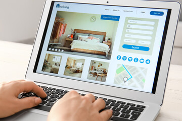 Woman with laptop booking room in hotel online, closeup