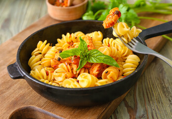 Frying pan with tasty pasta and chicken on table, closeup