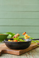 Frying pan with tasty pasta and chicken on table