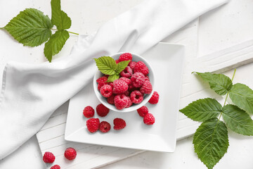Bowl with ripe raspberries on white background