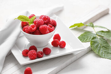 Bowl with ripe raspberries on white background