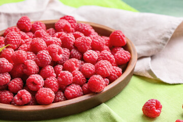 Plate with ripe raspberries on table