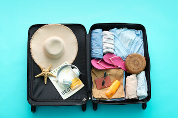 Packed suitcase with beach accessories on color background. Travel concept