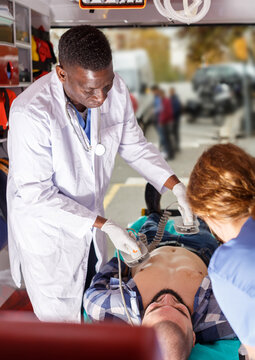 Afro emergency doctor using defibrillator for providing medical care to patient