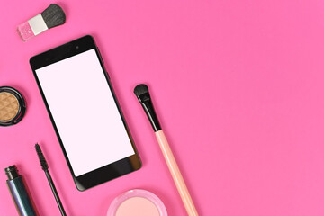 Flat lay with blank black smart phone with empty white screen and  makeup beauty products on pink...