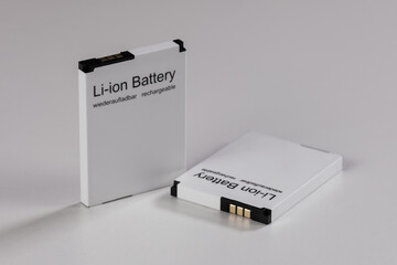 Zwei kleine flache Lithium-Akkus auf einem hellen Hintergrund (Li-ion Battery / Akku) - einer...
