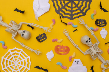 Handmade Halloween decor and skeleton, gummy worms on yellow background. Halloween background. Top...