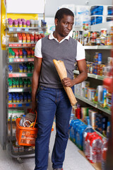 African man with shopping cart full of goods in supermarket