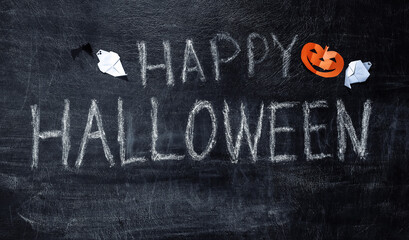 Chalk lettering Happy Halloween on a chalk board with Halloween decor