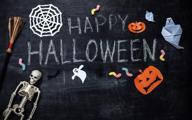 Chalk lettering Happy Halloween on a chalk board with Halloween decor