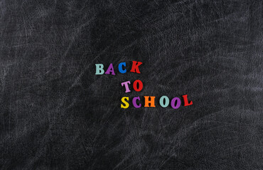 Text back to school from colored letters on a chalk board background.