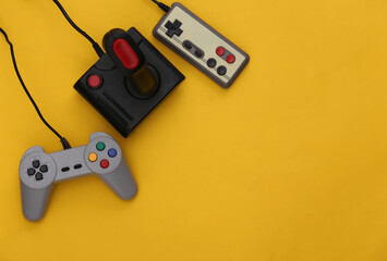 Set of different retro gamepads and joysticks on a yellow background. Video game. Flat lay, top view, copy space © splitov27