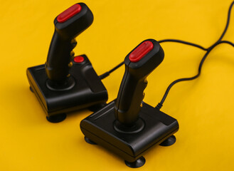 Two retro joysticks on yellow background. Gaming, video game competition.