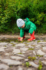 Child. A little boy in a green jacket and red boots plays in the swamp.
Carefree childhood. Happy child concept. Happy childhood.
He screams and laughs, has fun outside in the swamp.