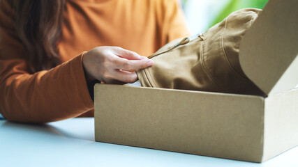 A woman receiving and opening a postal parcel box of clothing at home for delivery and online...