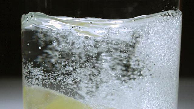 Lemon wedge being dropped from top of frame into a glass of carbonated water - SLOW MOTION 240 frames per second (240p 240fps) - Shot in 2K exported as 1080p