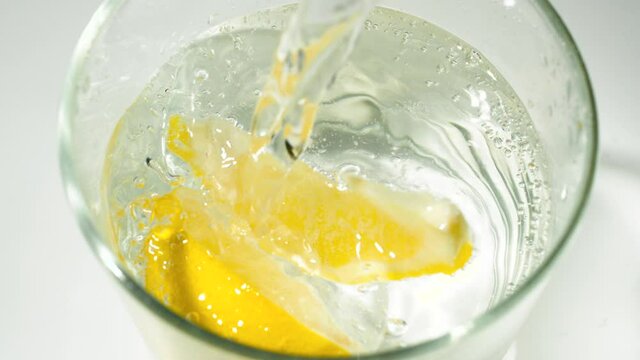 Carbonated water being poured into glass with lemon wedges in SLOW MOTION 240fps - Shot top down locked off on tripod - Shot in 2K exported to 1080p