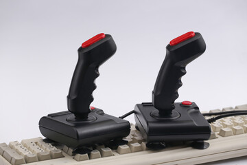 Retro joysticks on old pc keyboard. White background. Attributes 80s, gaming