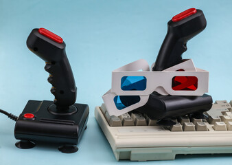 Retro joysticks with old pc keyboard and 3d glasses. Blue background. Attributes 80s, gaming