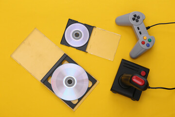 Retro gamepad and joystick, CD's on blue yellow background. Gaming, video game competition. Top view