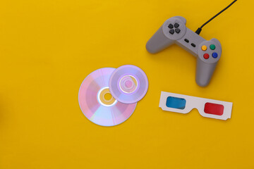 Retro gamepad and CD's, 3d glasses on yellow background. Top view