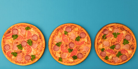 Three pizzas on the blue azure background. Pizza isolated. Banner with copy space for text or logo. Italian cuisine.