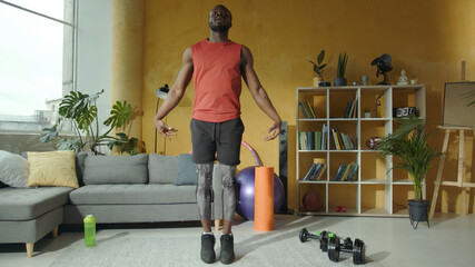 Athletic african american man in sportswear doing warm-up exercise in living room. Muscular handsome sports guy working out at home. Self-isolation. Sports.