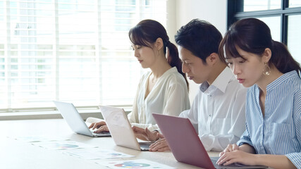 並んでPC作業する人々　ビジネスとチームワーク