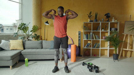 Strong muscular black man in sportswear stretching his arms doing shoulder circles warming up...