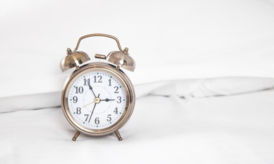 Classic alarm clock on bed.