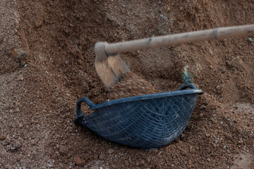 Black plastic clam-shell shaped basket used for transporting sand in the contruction site.