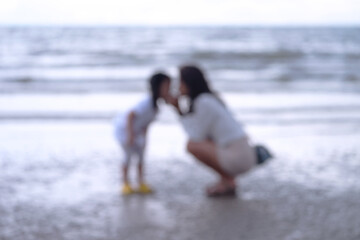 Blurry image of mother and daughter about to kiss each other on a beach close to the sea