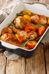 Summer food chicken legs baked in with fresh plums and rosemary close-up in a baking dish on the table. vertical