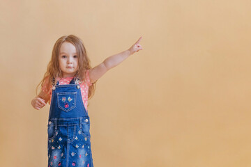 little child raising her forefinger от yellow background. copy space