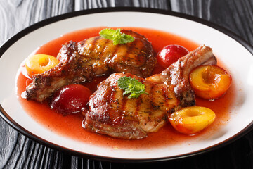 Fried spicy pork chop with fresh plums and fruit sauce close-up in a plate on the table. horizontal