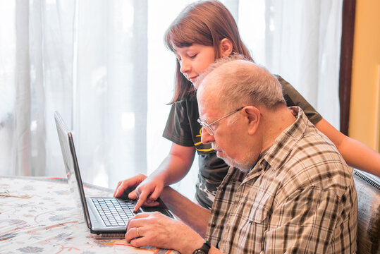 granddaughter is helping her grandfather to use a pc