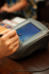 受付でカード払いのセキュリティのサインをする女性