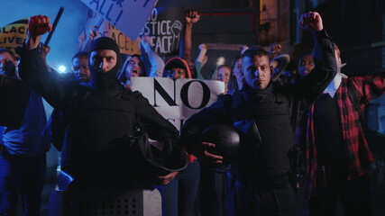 Fototapeta na wymiar Black lives matter. Two cops support the protest holding their helmets strike among group of activists. Multi-ethnic protesters rebel against violence, inequality, racism.