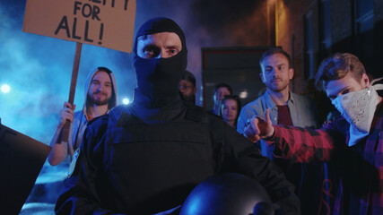 Positive caucasian policeman walks through thankful crowd of protesters. Hopeful multi-ethnic...