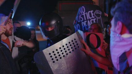 Violent street protesters fight with the policeman on street at night. Police officer trying to...