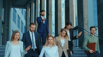 Fototapeta premium Professional company staff walking downstairs at office building. Successful and ambitious young team of co-workers and female boss. Cooperation. Career.