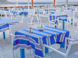 Blue table and gray chairs in a typical tavern in Greece with sea in the background
