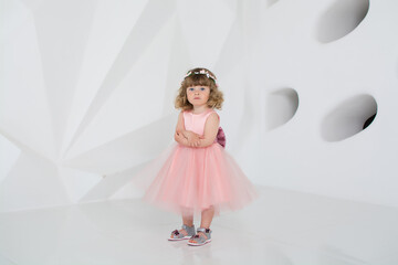 Fototapeta na wymiar little girl in pink dress. young woman in a bathroom. Beautiful girl in long dress smiles. A child in a white room. Elegant dress on the girl 