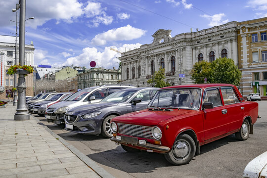 Red VAZ-2101 on the Constitution Square in Kharkiv (Ukraine), close-up. A row of cars parked on the street against the background of ancient buildings